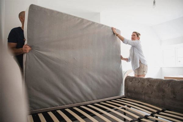 Pareja trasladando el colchón a la estructura de la cama - SUNSGOODS - SUNSGOODS Pareja moviendo un colchón hacia el marco de la cama