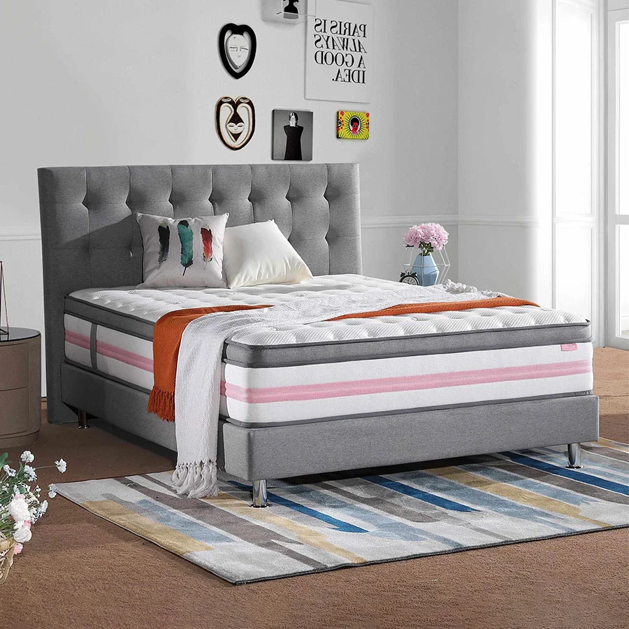 Cama gris con cabecero capitoné y decoración vibrante.