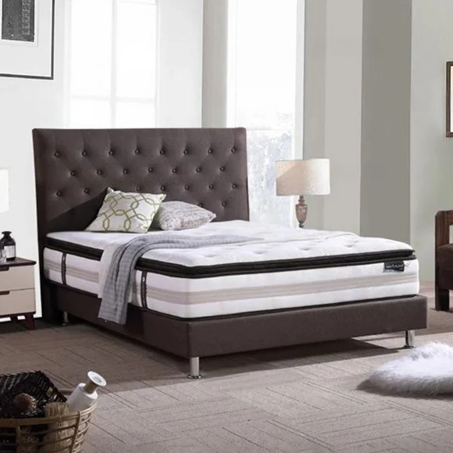 Lujosa estructura de cama tapizada en color marrón con almohadas incluidas.